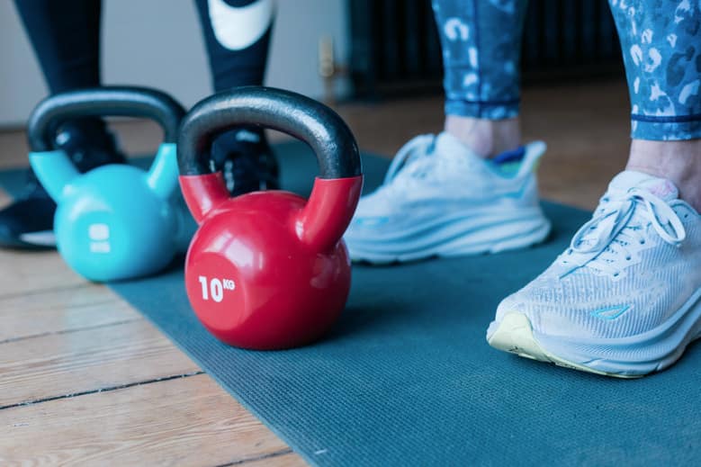 Why should women exercise? Two kettle bells in front of someone's feet